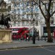 Busy executives walking though LinkedIn. Statue in fore, red bus in background.